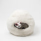 Cat lying inside a fluffy sheepskin white pet bed on a white background | Natural, non‑toxic pet nest for cats and small dogs | Cozy, handmade pet furniture, natural wool and sheepskin

