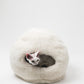 Cat peeking out from a fluffy white pet bed on a white background  | Natural, non‑toxic pet nest for cats and small dogs | Cozy, handmade pet furniture, natural wool and sheepskin


