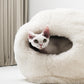 Cat peeking out from a fluffy white sheepskin pet bed in a minimalistic room. | Natural, non‑toxic pet nest for cats and small dogs | Cozy, handmade pet furniture, natural wool and sheepskin

