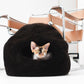 Cat peeking out from a black cat bed with a chair in the background | Natural, non‑toxic pet nest for cats and small dogs | Cozy, handmade pet furniture, natural wool and sheepskin


