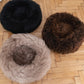 Three Round Natural Sheepskin Pet Beds - Black from Mellow Pet Store on a wooden floor.