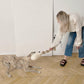 A woman playing with a dog on the floor, surrounded by Mellow Pet Store's Natural Sheepskin Dog Tug Toy.