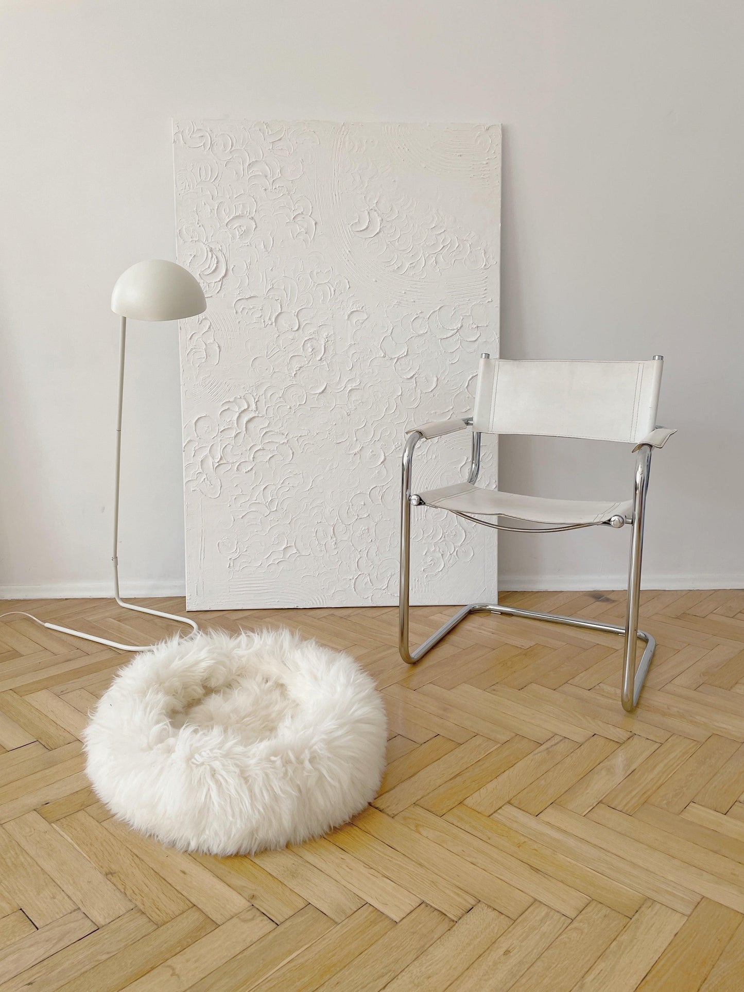 A Round Natural Sheepskin Pet Bed from Mellow Pet Store is resting on a wooden floor.